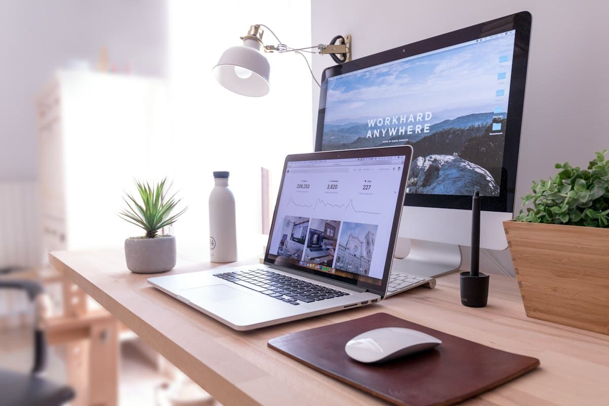 A tidy desk with a website open on a laptop and monitor